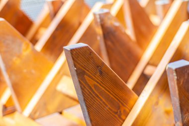 Yüksek dokuya ve sıcak ışığa sahip ahşap taburelere yakın çekim. Üst üste binen ahşap yüzeylerin oluşturduğu soyut geometrik desen.