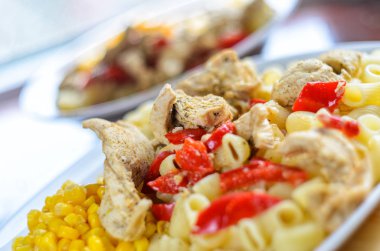 Sıcak makarna tavuk göğsü et ve sebze ahşap masa, yakın çekim üzerinde büyük beyaz plaka ile. Gıda arka plan