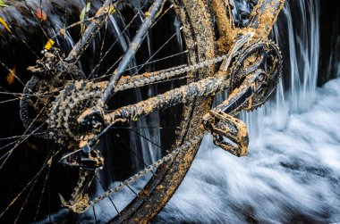Kirli dağ bisikleti bir dere küçük şelale karşı duruyor. Kirli zinciri sürücü dağ bisikleti yakın çekim. Bir bisiklet kavram Temizleme