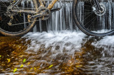 Kirli dağ bisikleti bir dere küçük şelale karşı duruyor. Kirli zinciri sürücü dağ bisikleti yakın çekim. Bir bisiklet kavram Temizleme