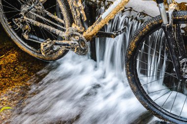 Kirli dağ bisikleti bir dere küçük şelale karşı duruyor. Kirli zinciri sürücü dağ bisikleti yakın çekim. Bir bisiklet kavram Temizleme