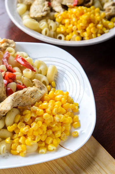 Sıcak makarna tavuk göğsü et ve sebze ahşap masa, yakın çekim üzerinde büyük beyaz plaka ile. Gıda arka plan