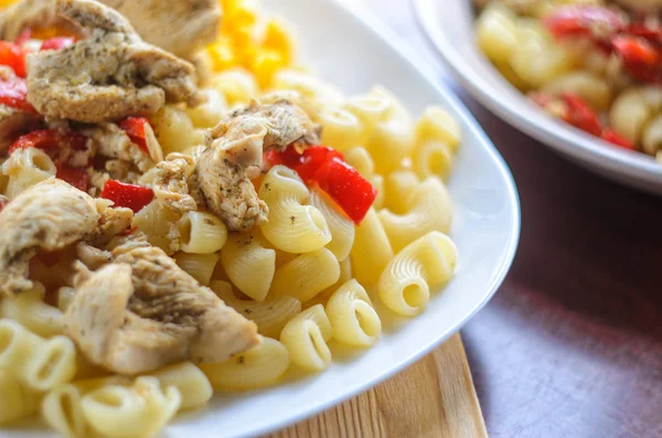 Sıcak makarna tavuk göğsü et ve sebze ahşap masa, yakın çekim üzerinde büyük beyaz plaka ile. Gıda arka plan