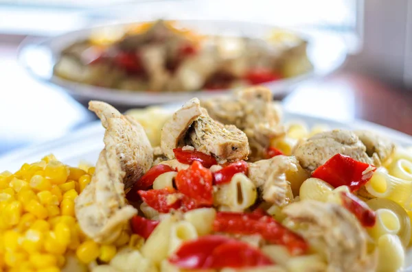 Sıcak makarna tavuk göğsü et ve sebze ahşap masa, yakın çekim üzerinde büyük beyaz plaka ile. Gıda arka plan