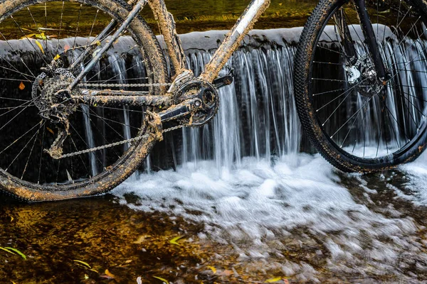 Kirli dağ bisikleti bir dere küçük şelale karşı duruyor. Kirli zinciri sürücü dağ bisikleti yakın çekim. Bir bisiklet kavram Temizleme