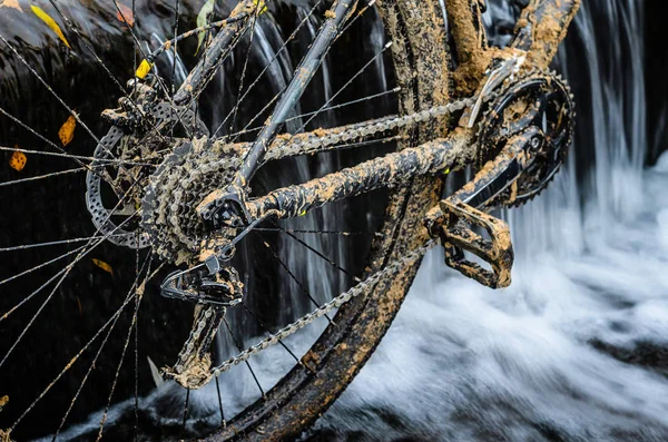 Kirli dağ bisikleti bir dere küçük şelale karşı duruyor. Kirli zinciri sürücü dağ bisikleti yakın çekim. Bir bisiklet kavram Temizleme