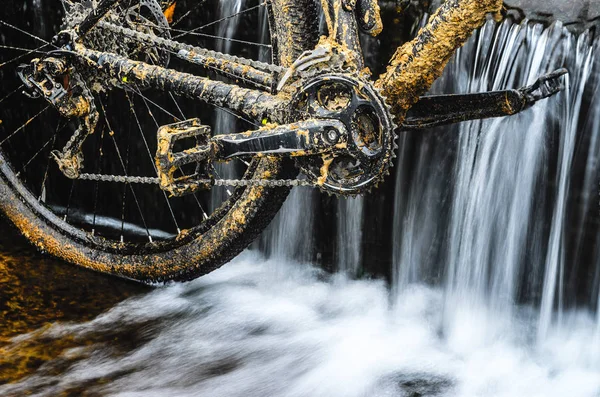 Kirli dağ bisikleti bir dere küçük şelale karşı duruyor. Kirli zinciri sürücü dağ bisikleti yakın çekim. Bir bisiklet kavram Temizleme