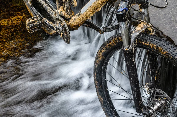 Kirli dağ bisikleti bir dere küçük şelale karşı duruyor. Kirli zinciri sürücü dağ bisikleti yakın çekim. Bir bisiklet kavram Temizleme