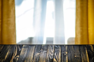 Boş koyu ahşap masa önünde oturma odasında pencere perdeleri arka plan bulanık. Ürün görüntüleme için alay. Senin düzen için boş