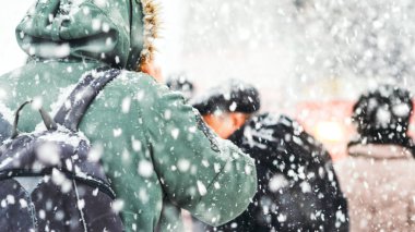 Bir kar fırtınası sırasında telefonda konuşurken kapüşonlu adam. Blizzard bir kentsel ortamda. Kar yağışı otobüs durağı insanlar. Kış hava arka plan