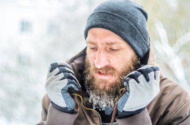 Gri bir şapka ve kahverengi bir ceket uzun sakallı genç bir adam portresi buz sarkıtları ile kaplı. Eldivenli elleri yaka yukarı çekin. Frost kavramı