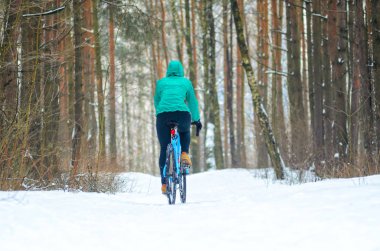 Bisikletçi cyclocross bisiklet parkurları kışın karlı ormandaki üzerinde. Kış egzersiz açık havada kavramı