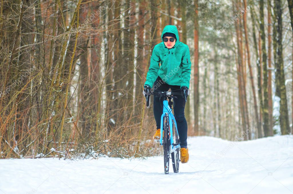 Cyclist on cyclocross bike trails in the snowy forest in winter. Winter workout outdoors concept