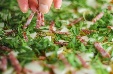 Pizza yapma işlemi. Mantar, ruccola, domates, mozzarella peyniri, sarmısak ve sos İtalyan biberli pizza. Chef malzemeler pizza için ekler.
