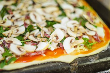 Pizza yapma işlemi. İtalyan biberli pizza mantar, ruccola, domates, mozzarella peyniri, sarmısak ve sos ile