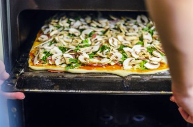 Pizza yapma işlemi. Mantar, ruccola, domates, mozzarella peyniri, sarmısak ve sos İtalyan biberli pizza. Şef biberli pizza fırından çeker. Taze pişmiş biberli Pizza