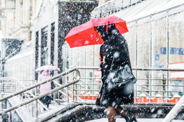 Blizzard bir kentsel ortamda. Kırmızı şemsiye kar yağışı içinde olan bir kadın silueti. Soyut bulanık kış hava arka plan.