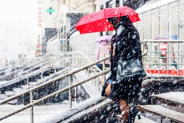 Blizzard bir kentsel ortamda. Kırmızı şemsiye kar yağışı içinde olan bir kadın silueti. Soyut bulanık kış hava arka plan.