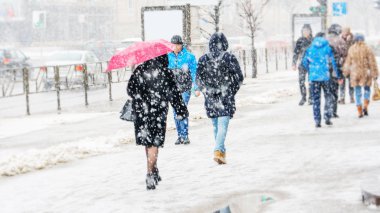 Blizzard bir kentsel ortamda. Kırmızı şemsiye insanlar kar yağışı acele bir kalabalık içinde olan bir kadın silueti. Soyut bulanık kış hava arka plan.