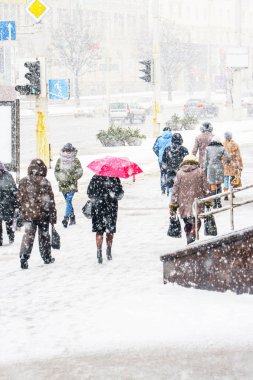 Blizzard bir kentsel ortamda. Kırmızı şemsiye insanlar kar yağışı acele bir kalabalık içinde olan bir kadın silueti. Soyut bulanık kış hava arka plan.
