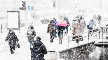 Blizzard bir kentsel ortamda. Kırmızı şemsiye insanlar kar yağışı acele bir kalabalık içinde olan bir kadın silueti. Soyut bulanık kış hava arka plan.