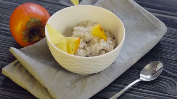 Une nourriture saine. Farine d'avoine au kaki dans un bol profond vue sur le dessus. Cuisson petit déjeuner sain- ajout de tranches de kaki .