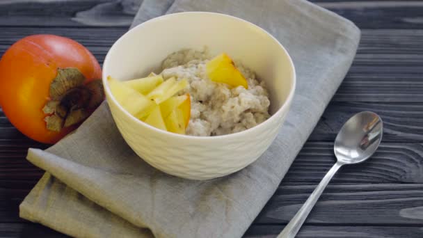 Une nourriture saine. Farine d'avoine au kaki dans un bol profond vue sur le dessus. Cuisiner le petit déjeuner sain- ajouter kiwi 