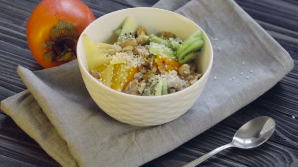 Healthy Food Oatmeal Persimmon Kiwi Walnuts Sesame Seeds Deep Bowl — Stock Video