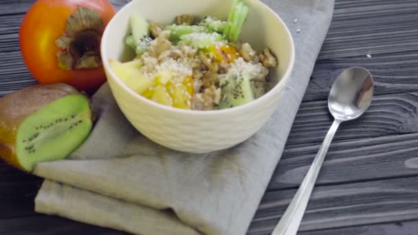 Une nourriture saine. Farine d'avoine au kaki, kiwi, noix et graines de sésame dans un bol profond vue du dessus 