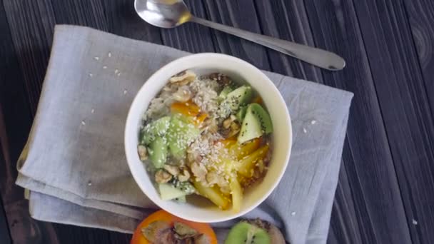 Une nourriture saine. Farine d'avoine au kaki, kiwi, noix et graines de sésame dans un bol profond vue du dessus 