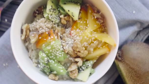 Une nourriture saine. Farine d'avoine au kaki, kiwi, noix et graines de sésame dans un bol profond vue du dessus 