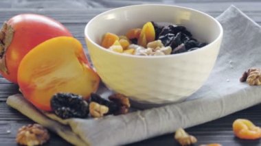 Hurma, kuru kayısı, kuru erik, ceviz ve susamlı kaşık ile birlikte derin bir kasede yulaf ezmesi. Sağlıklı yemek.