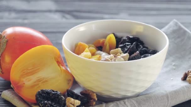 燕麦片在一个深碗里 勺子里伸出来 里面有柿子 干杏仁 核桃和芝麻 健康食品 — 图库视频影像