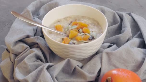 深いボウルにドライアプリコット プルーン カボチャの種とオートミール 柿です 健康的な朝食を作る 健康食品 — ストック動画