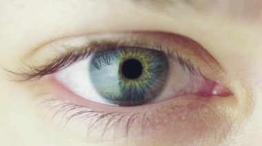 Genç bir kadının güzel mavi gözü etrafına bakıyor ve göz kırpıyor. Göz bebeği daraltma işlemi. Göz Kırpan İnsan Gözü Döngülü