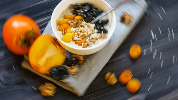 Oatmeal with Persimmon on a Black Wooden Table