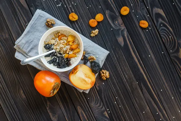 Oatmeal with Persimmon on a Black Wooden Table — Stock Photo, Image