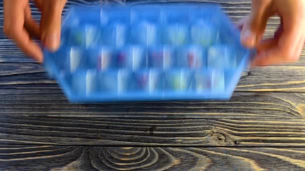 男人在木制桌子上扔冰块 用蓝色塑料模型做成新鲜的贝雷帽 顶视图 — 图库视频影像