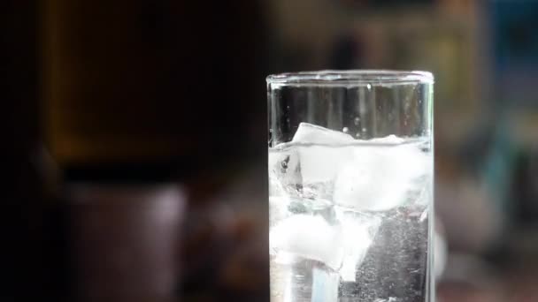 glaçons jetés dans un verre d'eau et mélanger avec une paille Gros plan 