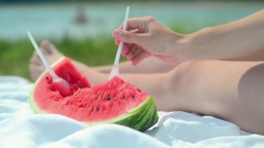 Genç bir kadın sahilde karpuz yiyor. Mutluluk, dinlenme, plaj. Sağlıklı bir yaşam tarzı. Yaz konsepti