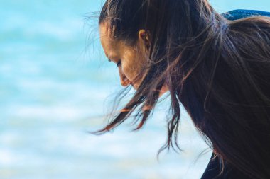 Uzun siyah dalgalı saçlı genç bir kadın.