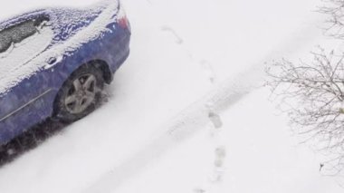Otoparktaki karda bir araba. Kış günü kar yağıyor. Kar fırtınası. Şehir kış arkaplanı