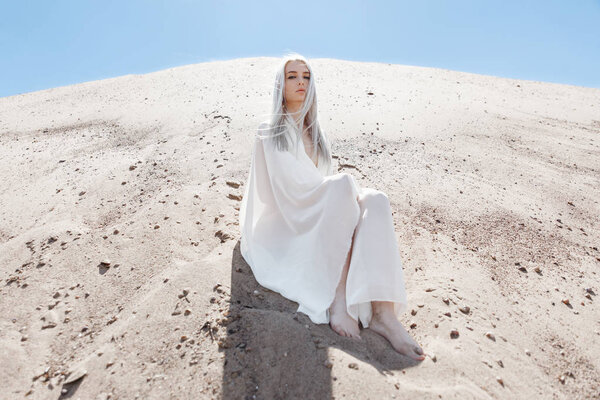 The girl with white hair among the sand mountains