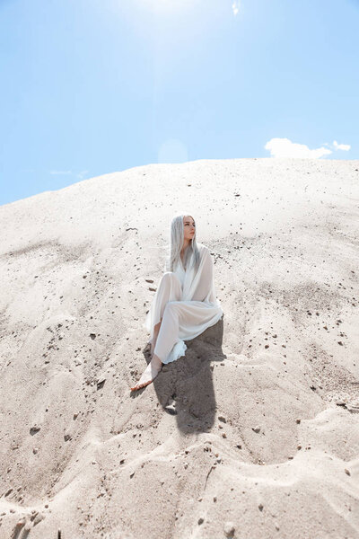 The girl with white hair among the sand mountains