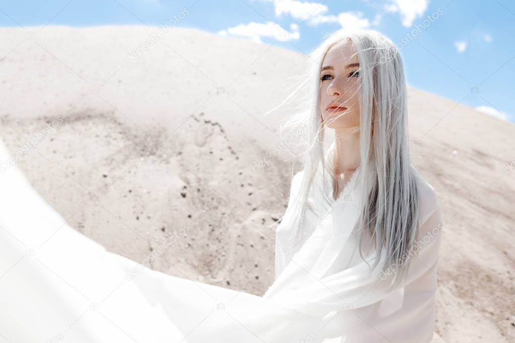 The girl with white hair among the sand mountains