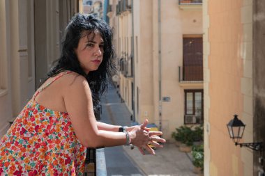 İspanyol kadın geleneksel bir mahallede balkondan manzaranın keyfini çıkarıyor.