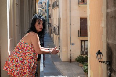 Valencia, İspanya 'da balkondan dışarı bakan düşünceli bir kadın.