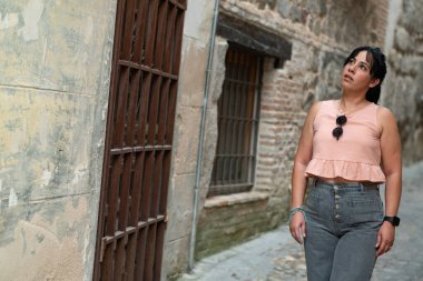 Dar, eski bir kasaba yolunu keşfeden kadın turist, tarihi mimariye bakıyor.