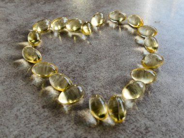 Dev bir kalbe yerleştirilmiş D3 vitamini kapsülleri.