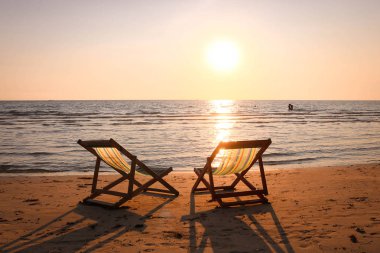 Plaj sandalyesini günbatımı zamanı tropikal plaj